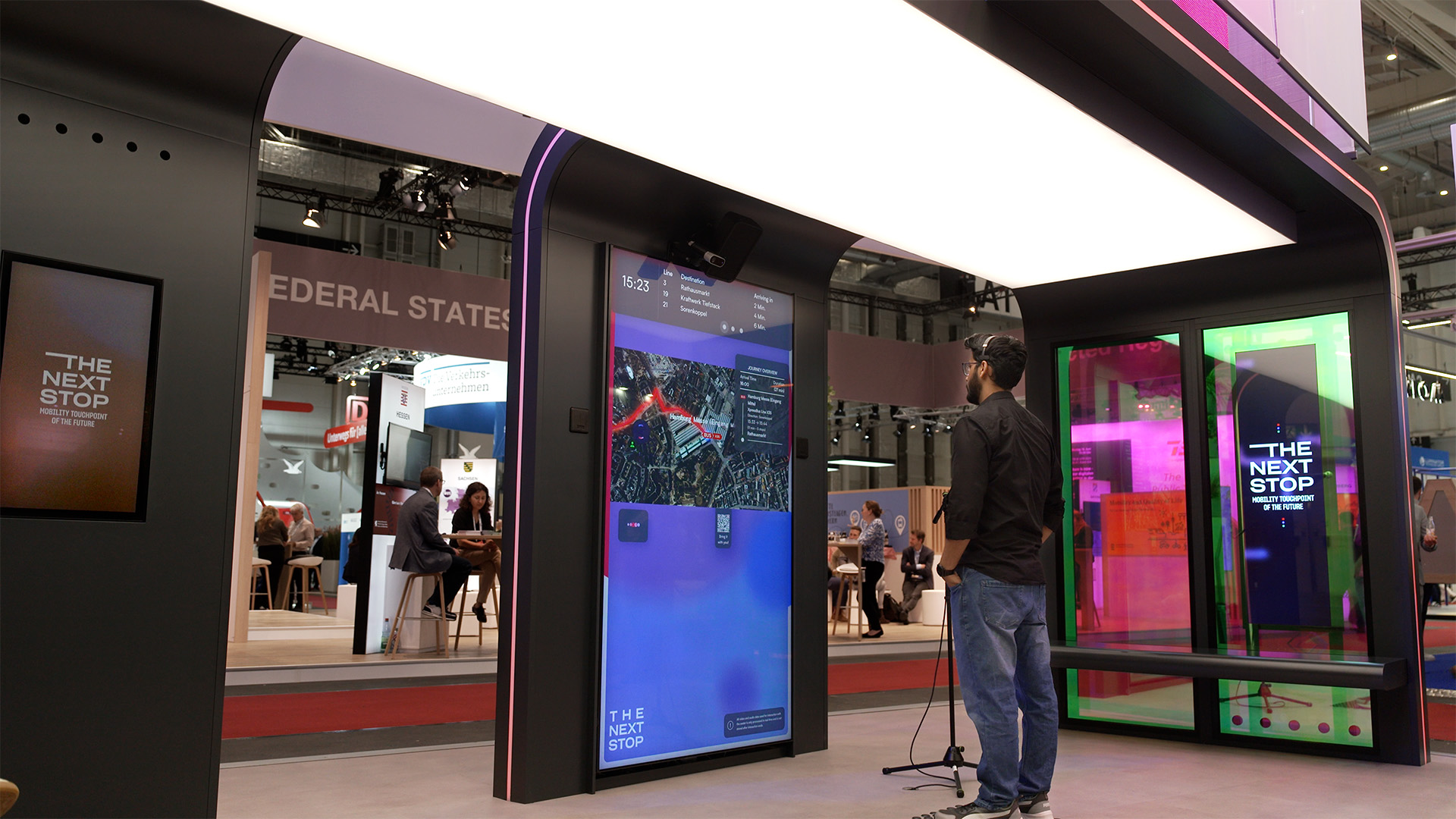 Interactive Mobility Touchpoint at UITP 2025 – The Next Stop by Luxoom Man interacting with a multilingual smart mobility touchpoint at UITP 2025, part of “The Next Stop” booth by Luxoom.